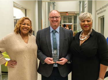 man with red hair wearing suit posing with glass award
